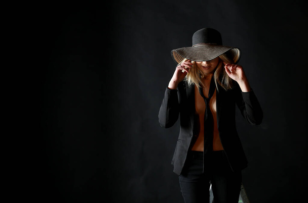 Belle femme en grand chapeau noir sur fond sombre
 - Photo, image