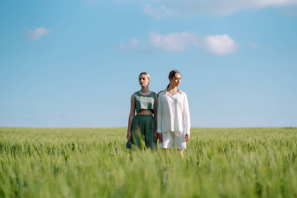 Two Beautiful woman in the green field. Nature, vacation, relax and lifestyle. Summer landscape. Fashion, style concept. - Fotografie, Obrázek