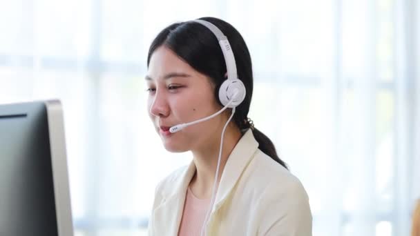 Gyönyörű ázsiai nő, ő egy call center alkalmazottja egy internetes és telefontársaság, ő a felelős a szolgáltatás és a segítségnyújtás az ügyfelek telefonon keresztül. Call center koncepció. - Felvétel, videó