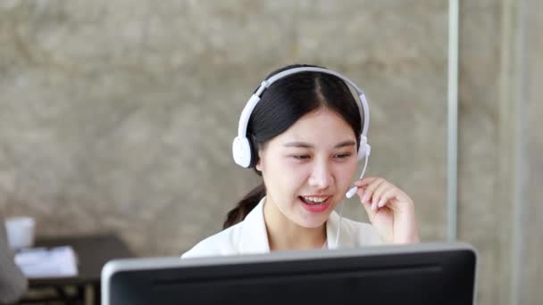 Beautiful Asian woman, she is a call center employee of an Internet and telephone company, she is responsible for providing service and assistance to customers through the phone. Call center concept. - Footage, Video