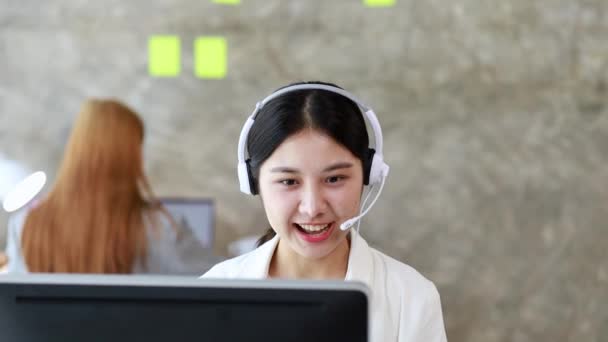 Güzel bir Asyalı kadın, bir internet ve telefon şirketinde çağrı merkezi çalışanı, telefon aracılığıyla müşterilere hizmet ve yardım sağlamaktan sorumludur. Çağrı merkezi kavramı. - Video, Çekim