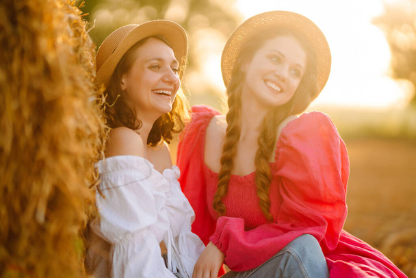 Two young women having fun  near haystack. Fashion concept. Nature, vacation, relax and lifestyle. Beautiful figures. Super mood. Summer concept. - Photo, Image