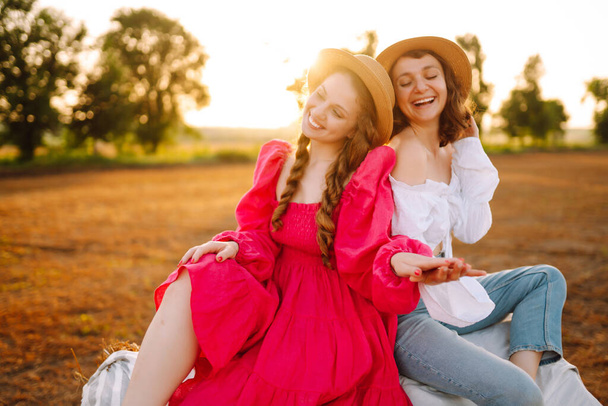 Two young women having fun  near haystack. Fashion concept. Nature, vacation, relax and lifestyle. Beautiful figures. Super mood. Summer concept. - Fotografie, Obrázek