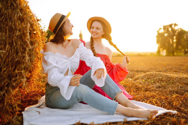 Two young women having fun  near haystack. Fashion concept. Nature, vacation, relax and lifestyle. Beautiful figures. Super mood. Summer concept. - Photo, image