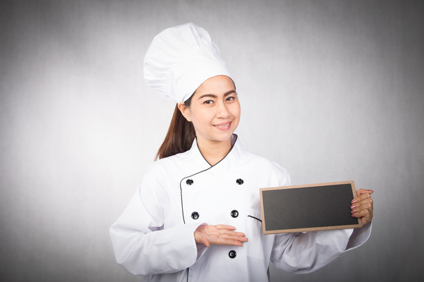 Nuori nainen kokki tilalla musta aluksella
 - Valokuva, kuva