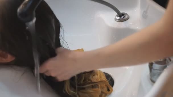 Fryzjerzy myją włosy swoich klientów szamponem i masują włosy, - Materiał filmowy, wideo