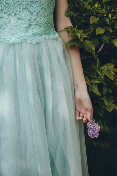 main d'une fille en robe turquoise tenant un lilas violet, verticale - Photo, image