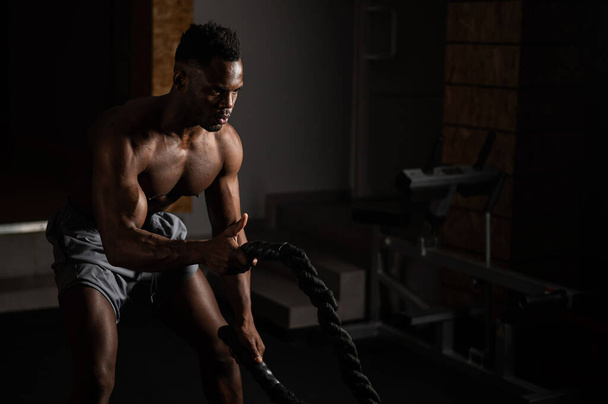 Attractive african american man with naked torso doing endurance exercises with trope - Foto, immagini