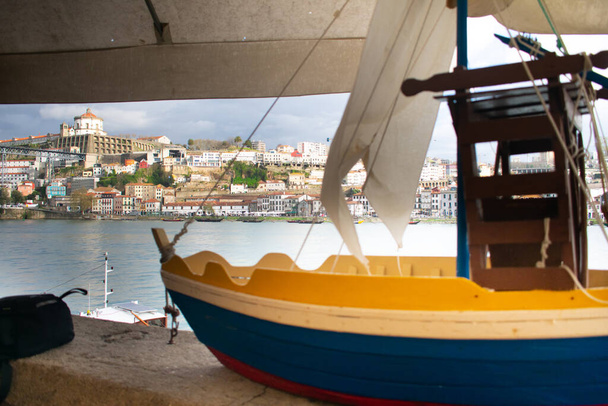 Wooden replica sailboat used to transport port wine with Rio Douro and Porto harbor in background - Photo, Image
