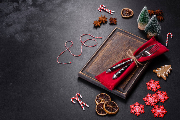 Vánoční stůl nastavení s prázdnou černou keramickou deskou, jedle větev a černé příslušenství na černém kameni pozadí - Fotografie, Obrázek