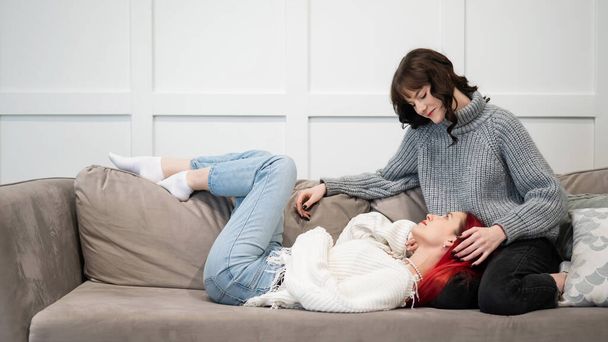 Young girls hugging while lying on the couch. Unisexual love - Foto, afbeelding