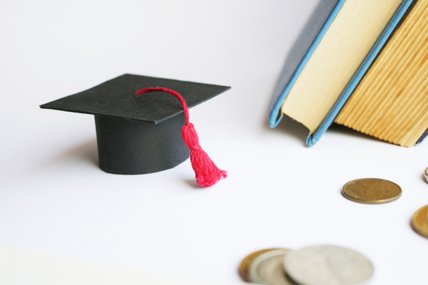 Выпускной колпачок с книгами и монетами. Концепция студенческого кредита. Академические стипендии  - Фото, изображение