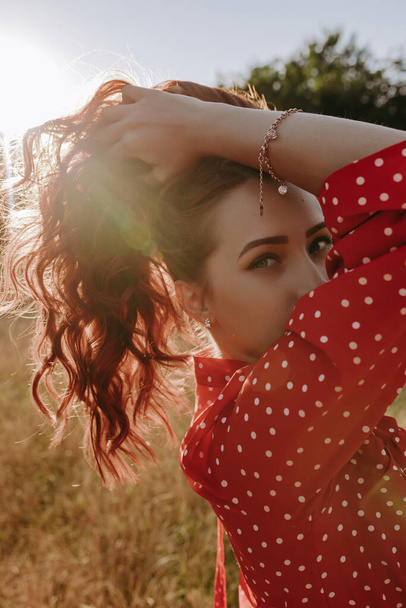 bella giovane donna che tiene i capelli per mano e posa su una macchina fotografica in mezzo al campo di grano - Foto, immagini