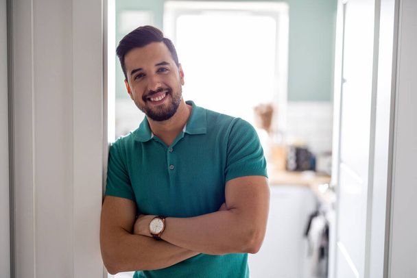 Sonriente hombre de pie en la puerta de la cocina    - Foto, imagen