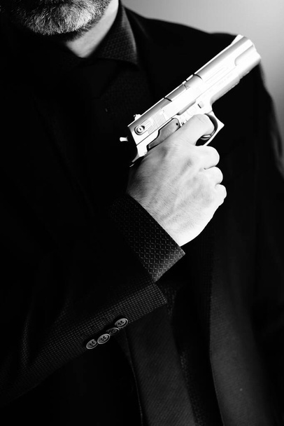 Dobře oblečený muž tajný agent detektiv špion nosí oblek a kravatu drží automatickou pistoli. - Fotografie, Obrázek