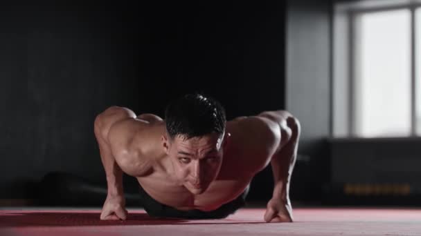 Fit young man does push ups in the gym. Mid shot - Footage, Video