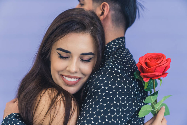attractive young couple holding each other, woman is holding a red rose . High quality photo - Photo, Image
