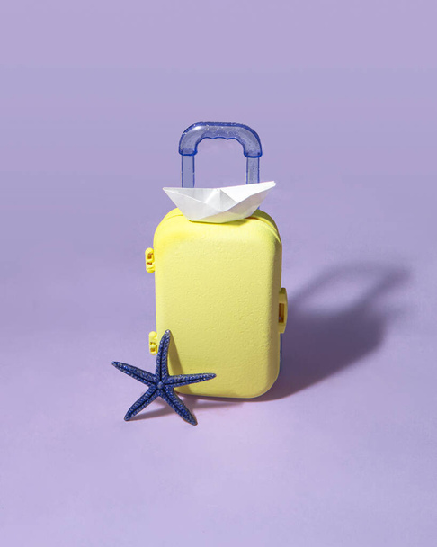 Minimale Reisezusammensetzung. Koffer auf pastellfarbenem lila Hintergrund. Kreatives Sommerferienkonzept. - Foto, Bild