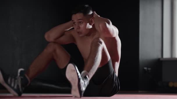Fitter junger Mann, der im Fitnessstudio auf seine Bauchmuskeln schlägt. Mittelschuss - Filmmaterial, Video
