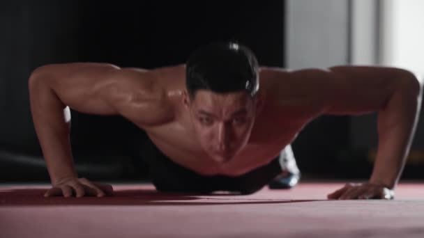 Fit young man does push ups in the training gym. Mid shot - Footage, Video