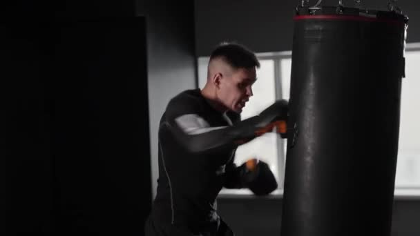Formda ve konsantre bir genç boksör spor salonunda kum torbasına vuruyor. Orta çekim - Video, Çekim