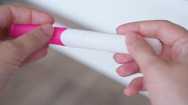 Vrouwelijke handen die een zwangerschapstest houden. Vrouw maken test - resultaat is positief, tonen twee lijnen. Zwangerschap concept, gezinsplanning. - Video