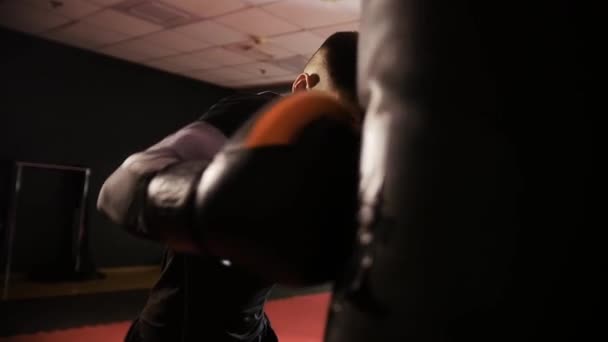 Box képzés - fit férfi rövid hajjal üti a boxzsákot lassított felvételen. Középső felvétel - Felvétel, videó