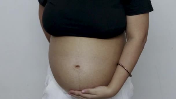 молодая беременная женщина показывает свою УЗИ с круглым животом под другим углом - Кадры, видео