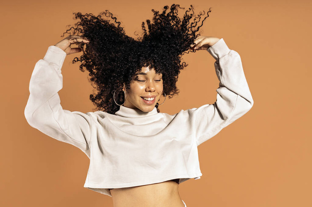Stock photo of beautiful african woman moving her curly hair in studio shot. - Zdjęcie, obraz