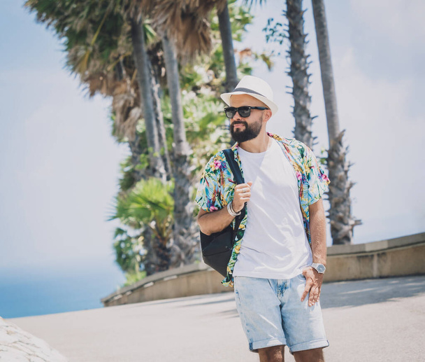 Young traveler man at summer holiday vacation with beautiful palms and seascapes at background. - Zdjęcie, obraz