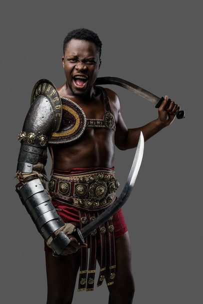 Фотография жестокого древнего гладиатора африканского этнического крика перед камерой. - Фото, изображение