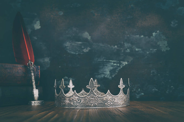low key image of beautiful queen or king crown and old book. fantasy medieval period - Foto, afbeelding