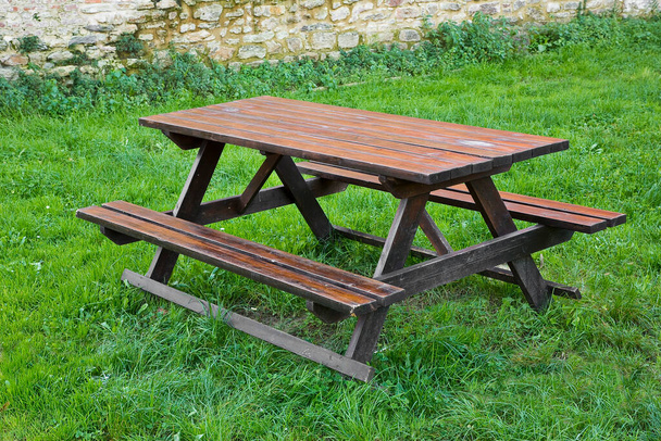 Kamu parkının yeşil çayırında boş ahşap piknik masası.. - Fotoğraf, Görsel