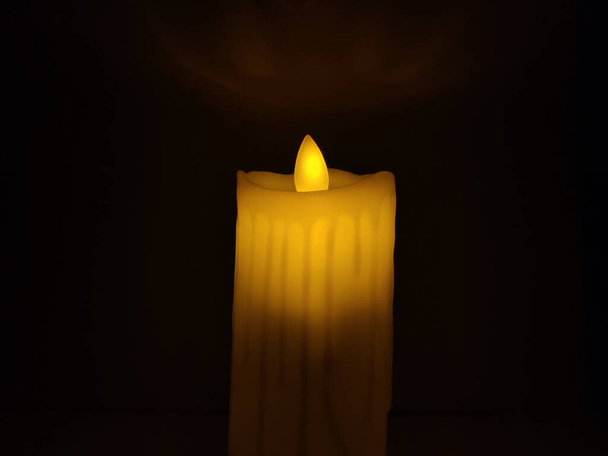 Bild einer gelben Kerze, die in der Nacht vor schwarzem Hintergrund geschossen wurde - Foto, Bild