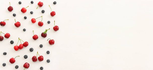 Top view image of colorful assorted mix of berries, blueberry and sweet cherry over wooden white background - Foto, Bild