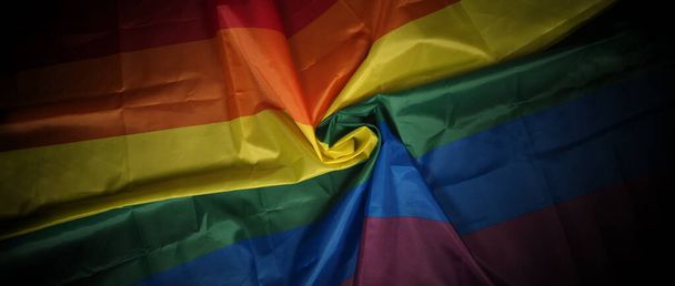 Bandiera LGBTQ pride su sfondo nero. Lgbt bandiera arcobaleno in mano gay. Rappresentare simbolo di libertà pace uguaglianza e amore e rispettare la diversità della sessualità. lesbica gay bi sexsual transgender queer. - Foto, immagini