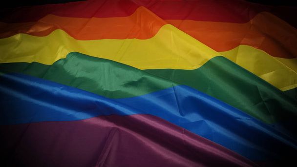 Bandera del orgullo LGBTQ sobre fondo negro. Bandera de arco iris Lgbt en la mano gay. Representar símbolo de la libertad la paz la igualdad y el amor y respetar la diversidad de la sexualidad. Lesbianas Gay Bi sexual Transgénero Queer. - Foto, imagen
