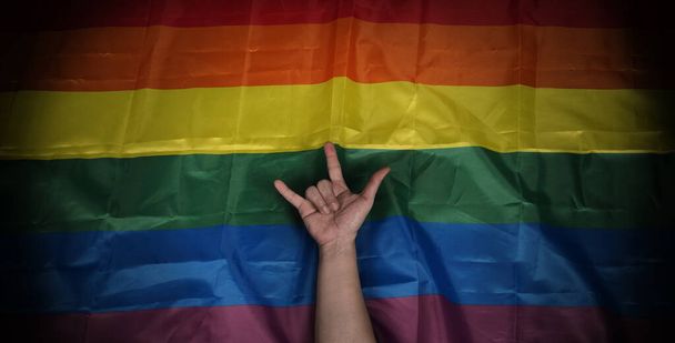 Bandera del orgullo LGBTQ sobre fondo negro. Bandera de arco iris Lgbt en la mano gay. Representar símbolo de la libertad la paz la igualdad y el amor y respetar la diversidad de la sexualidad. Lesbianas Gay Bi sexual Transgénero Queer. - Foto, Imagen
