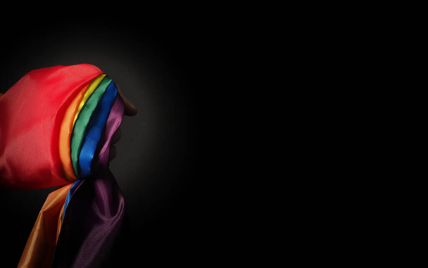 LGBTQ ylpeys lippu mustalla pohjalla. Lgbt sateenkaaren lippu homo kädessä. Edustaa vapauden symbolia rauhaa tasa-arvoa ja rakkautta sekä kunnioittaa seksuaalisuuden monimuotoisuutta. Lesbo homo bi seksuaalinen transsukupuolinen homo homo. - Valokuva, kuva