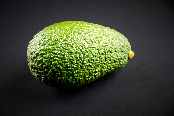 Fresh organic avocado isolated on a black background - Foto, afbeelding