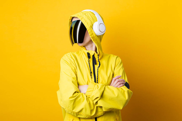Young woman in cyberpunk glasses with headphones in a yellow jacket on a yellow background. - Foto, Imagem