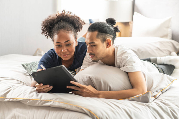 jeune couple à l'aide d'un ordinateur tablette au lit
 - Photo, image