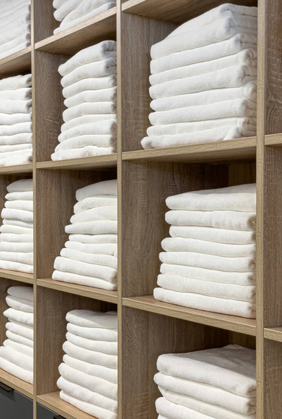 A toalha de banho e toalhas de banho para cores higiênicas e limpas são perfeitamente combinadas. Novas toalhas brancas são empilhadas nas prateleiras no armário - Foto, Imagem