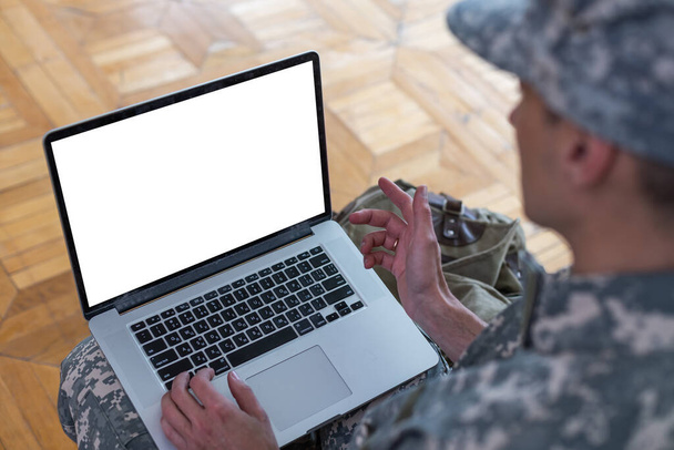 солдат в военной форме, использующий высокотехнологичный компьютер в штабе разведывательного центра. Фокус на дисплее ноутбука. - Фото, изображение