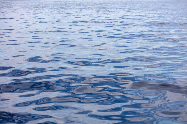 A tengervíz felszíne nyugodt, kis hullámokkal. Csendes óceán, mély kék háttér. Égei-tenger, Földközi-tenger - Fotó, kép