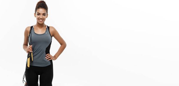 Sport, vzdělávání, životní styl a Fitness koncept - portrét krásné šťastné afroamerické ženy cvičení s skákání přes švihadlo. Izolované na bílém studio pozadí - Fotografie, Obrázek
