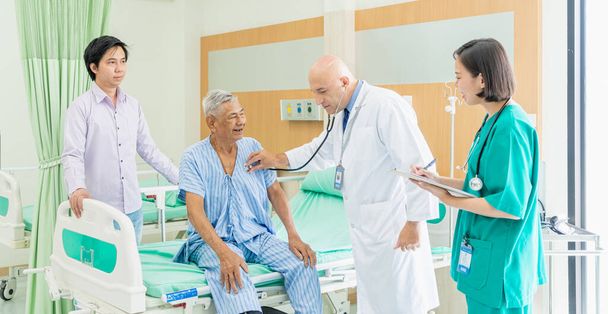 De arts en verpleegkundige controleren de oude senior man en praten over herstellen in het ziekenhuis., Medisch en gezondheidsconcept. - Foto, afbeelding