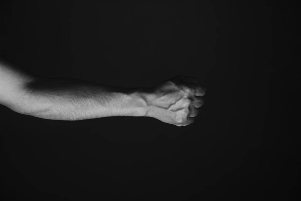 Brutale Männerhand mit hervorstehenden Adern, schwarzem Hintergrund. Schwarz-Weiß-Foto - Foto, Bild