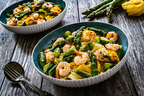 Tagliatelle with prawns and asparagus on wooden table  - Fotoğraf, Görsel