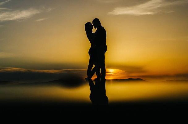 siluetti rakastava pari syleilee auringonlaskun aikaan - Valokuva, kuva